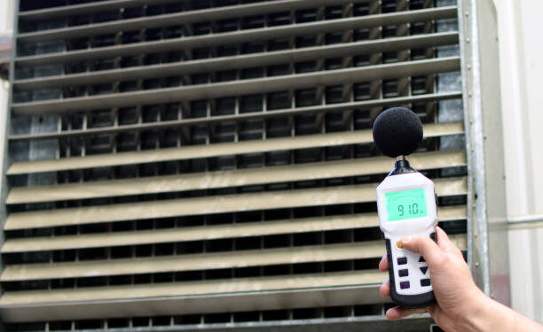 Sound level meter measuring the noise of industrial ventilation unit.