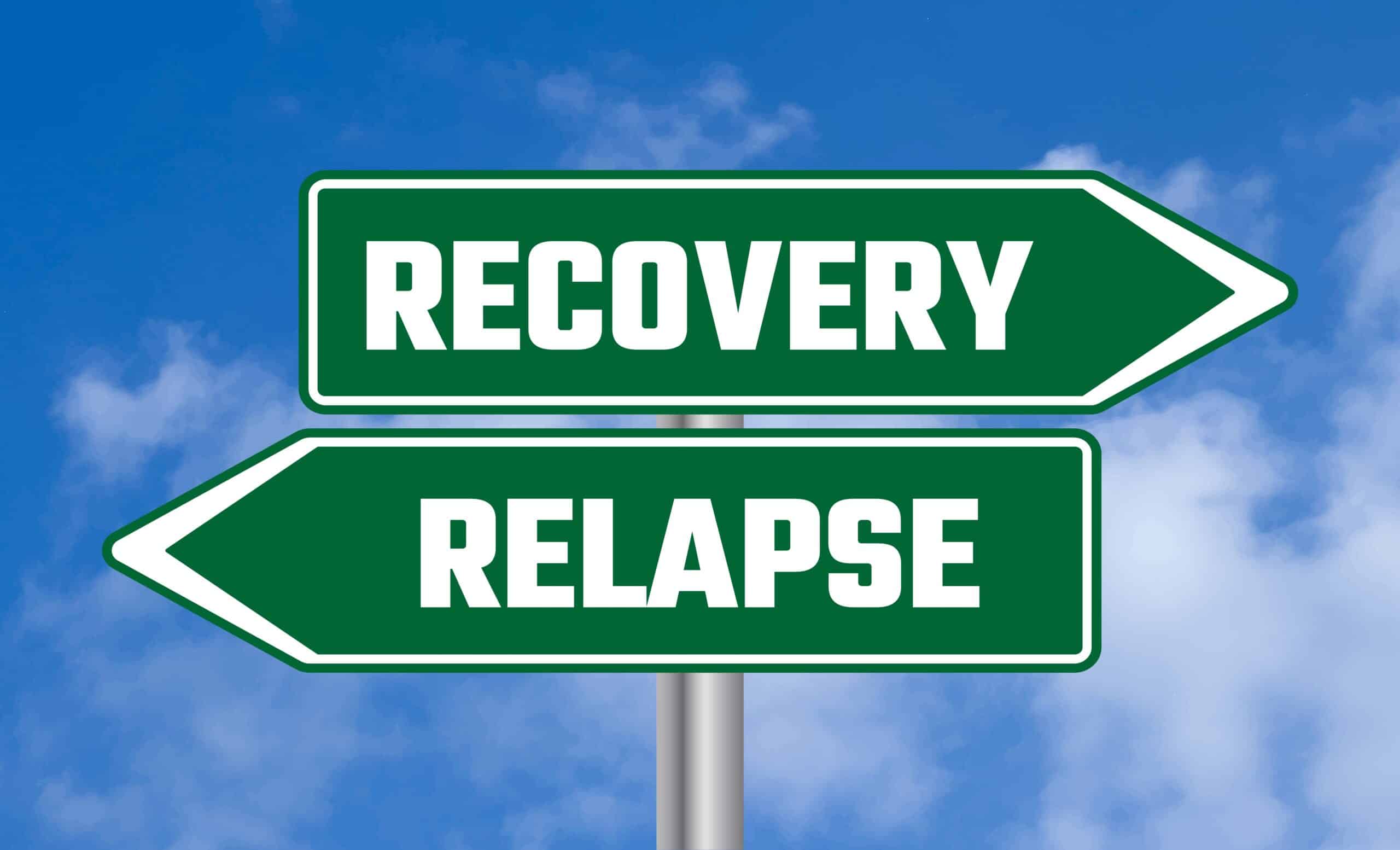 Two green directional signs against a blue sky with clouds; one points right and reads RECOVERY, the other points left and reads RELAPSE.